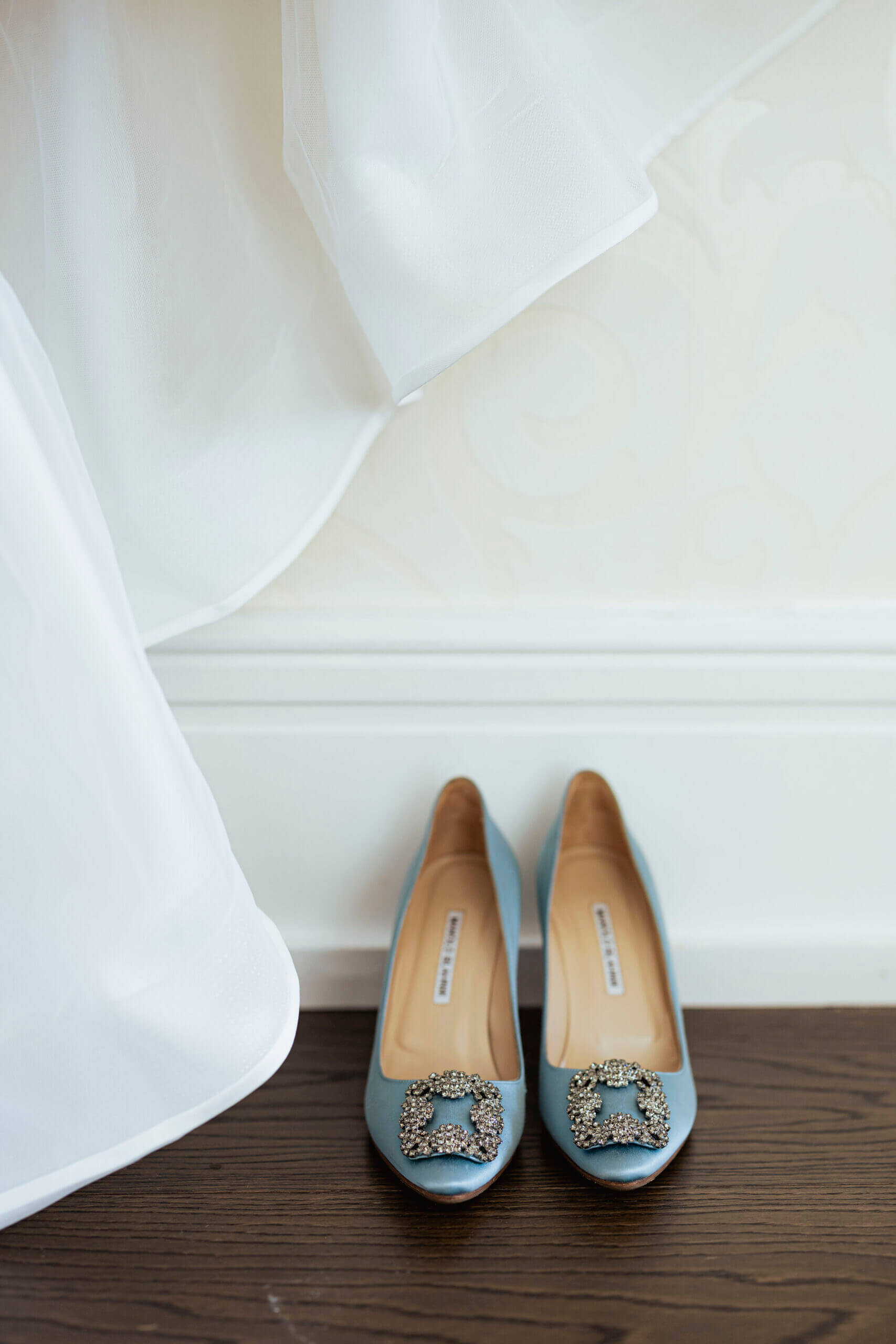 Blå manolo blahnik brudesko med dekorative spenner under en svevende kjole – fotografert av Anna O. Brambilla.