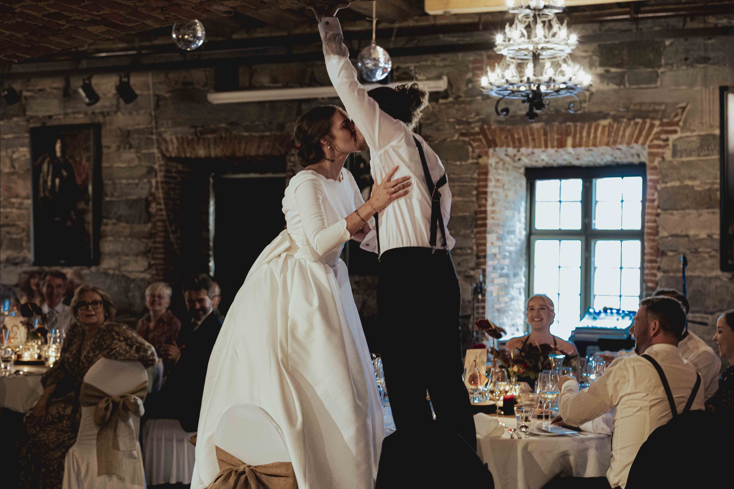 Kjærlighetsfullt blikk mellom Martine og Simen under bryllupsfotograferingen i Kongsberg. Bryllupsfoto av Anna O. Brambilla Documentary-style wedding photography capturing a joy during the reception Martine and Simen sharing a joyful moment with their guests during their wedding celebration at Søstrene Storaas, filled with heartfelt speeches and dancing.