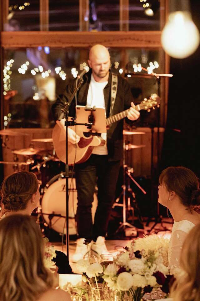 Solo musician performing with guitar at a cozy indoor wedding reception – photo by Anna O. Brambilla