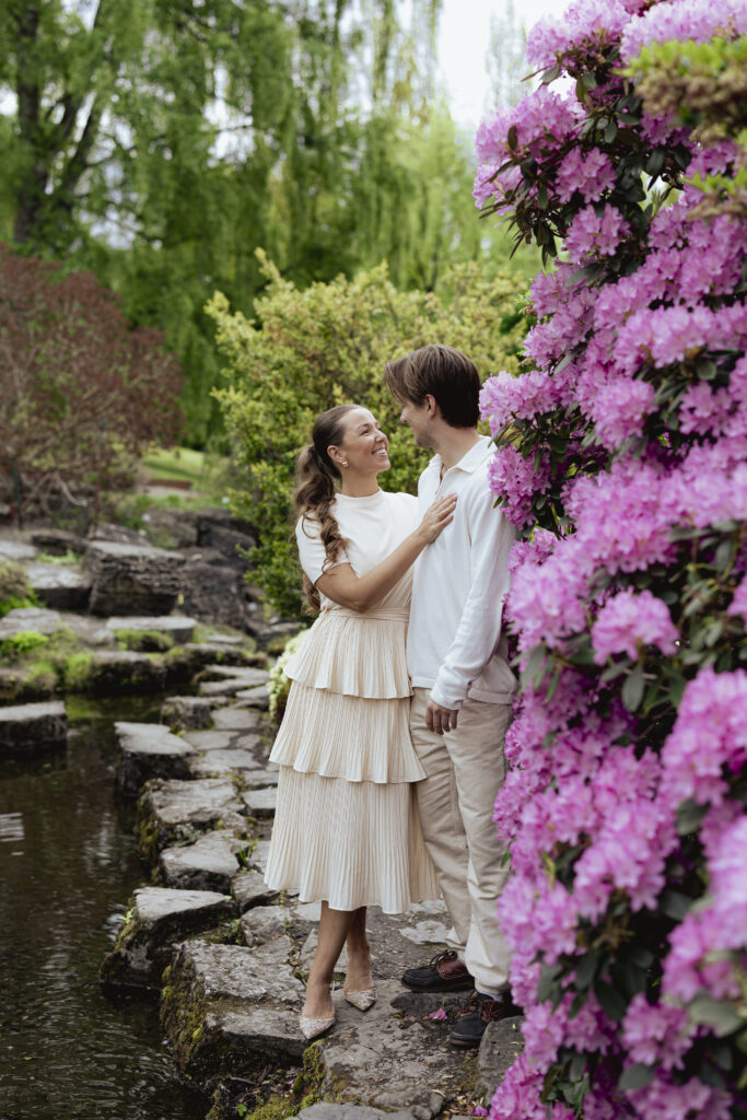 Joyful embrace in front of flowering bushes – couple photography in Oslo by Anna O Brambilla