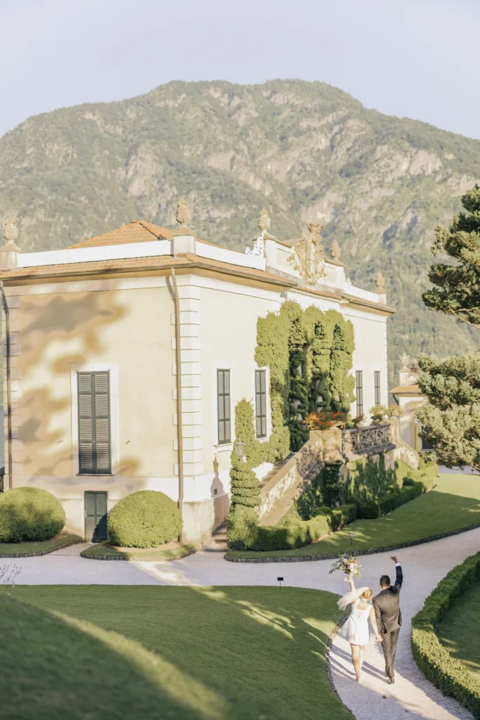 Bride and groom walking hand in hand through the gardens of Villa del Balbianello, celebrating after their elopement in Varenna. Photo by wedding photographer Anna O. Brambilla. Brudepar som går hånd i hånd gjennom hagen ved Villa del Balbianello etter elopement i Varenna. Foto av bryllupsfotograf Oslo Anna O. Brambilla.