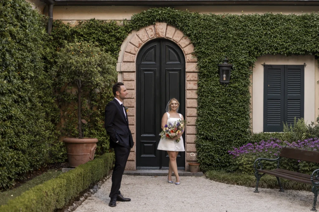 Bride and groom during their first look at Villa del Balbianello, surrounded by ivy-covered walls and rustic architecture. Photo by wedding photographer Anna O. Brambilla.