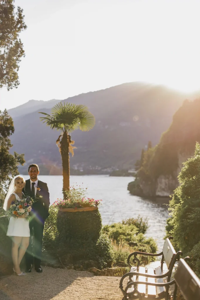 Bride and groom standing by a palm tree at sunset, overlooking Lake Como at Villa del Balbianello. Elopement in Varenna by Anna O. Brambilla. Brudepar ved palme i solnedgang med utsikt over Comosjøen ved Villa del Balbianello. Foto av bryllupsfotograf Oslo Anna O. Brambilla.