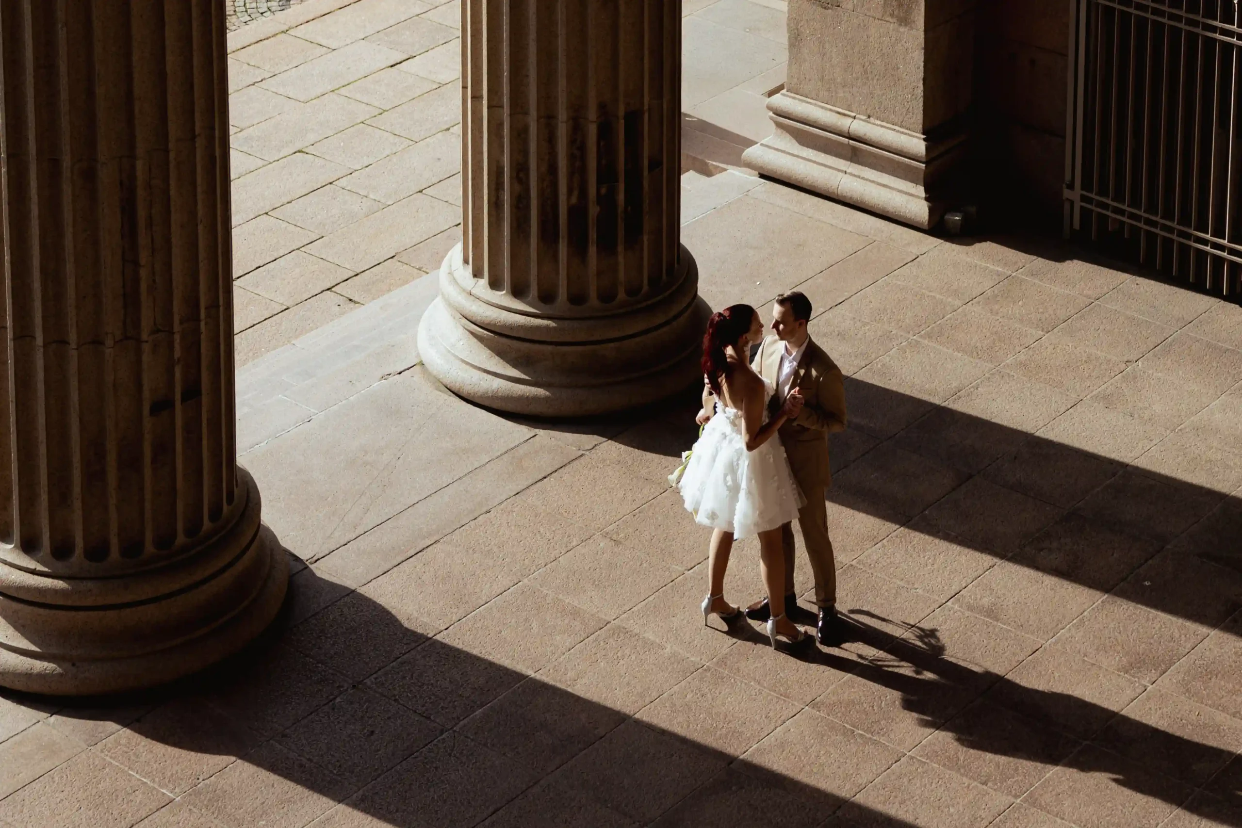 Brudepar som deler en intim dans mellom store søyler under et elopement i Oslo — fotografert av Anna O. Brambilla, bryllupsfotograf. Bride and groom sharing an intimate dance between grand columns during a city elopement in Oslo — photographed by Anna O. Brambilla, wedding photographer.