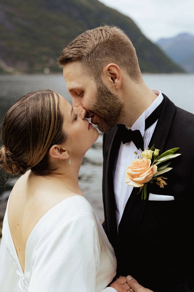 Nært portrett av brudepar med naturlig lys og fjord i bakgrunn