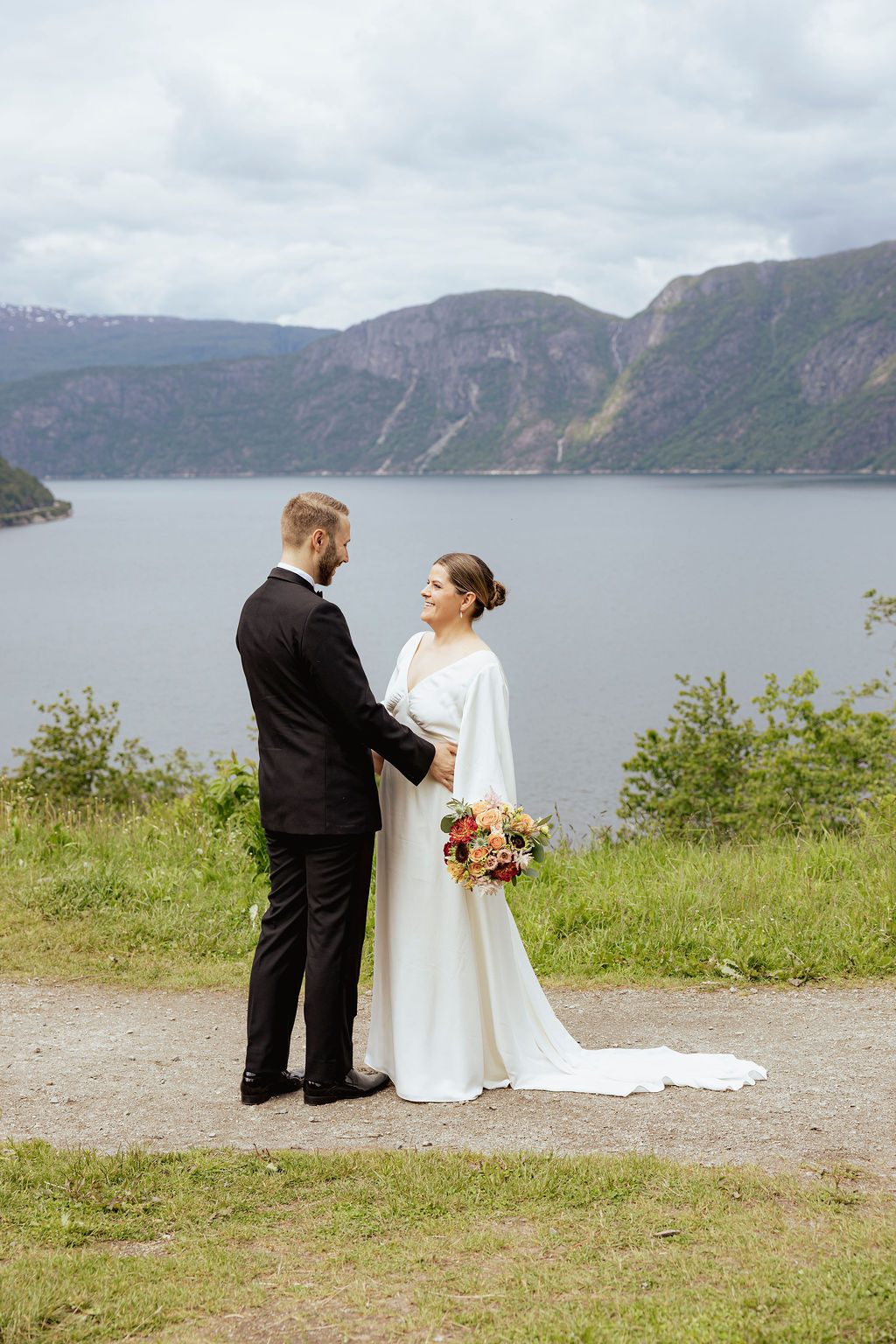 Brudepar ved vannet med utsikt over fjord og fjell