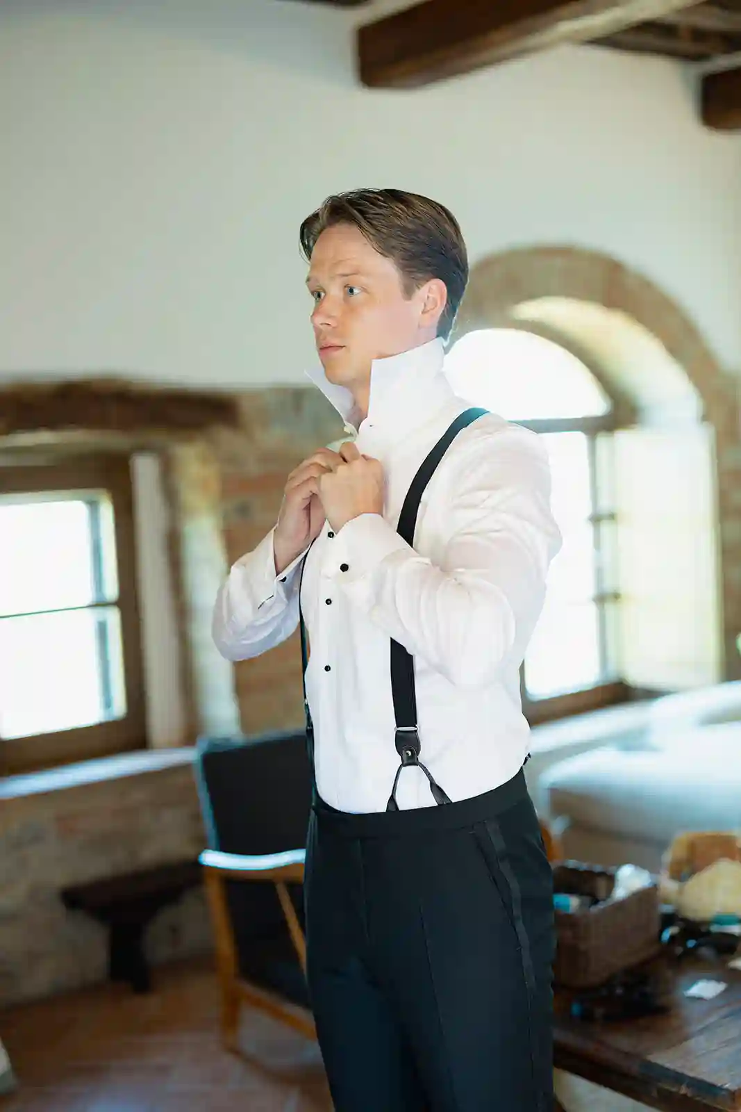 Brudgommen tar på sløyfe og bukseseler på bryllupsmorgenen i Toscana Groom putting on his bow tie and suspenders on the wedding morning in Tuscany