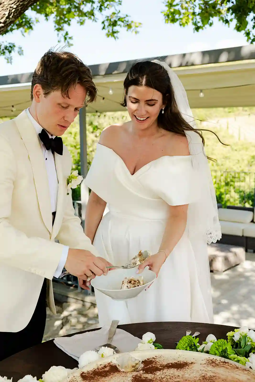 Brudeparet serverer tiramisu sammen under bryllupsfeiringen i Toscana Bride and groom serving tiramisu together during their wedding celebration in Tuscany