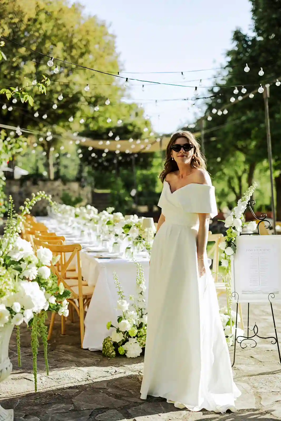 Bruden ved det blomsterdekkede middagsbordet før bryllupsmiddagen i Toscana Bride beside the flower-filled dinner table before the wedding dinner in Tuscany