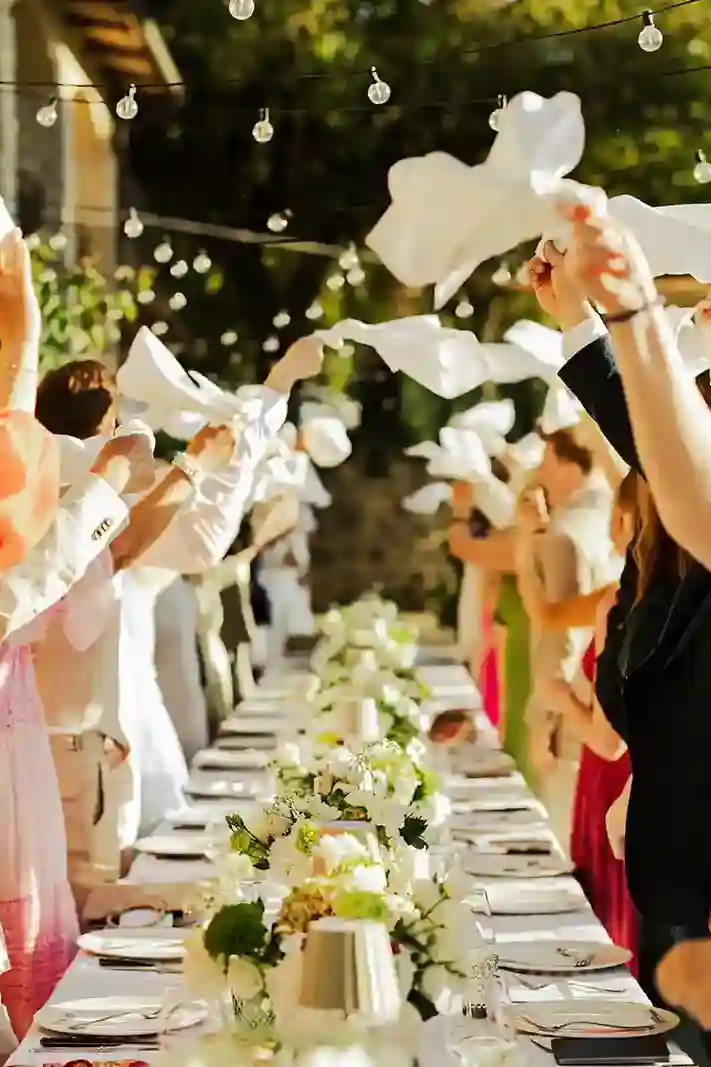 Bryllupsgjestene vifter med servietter over langbordet under middagen i Toscana Wedding guests waving napkins above the long dinner table during the reception in Tuscany