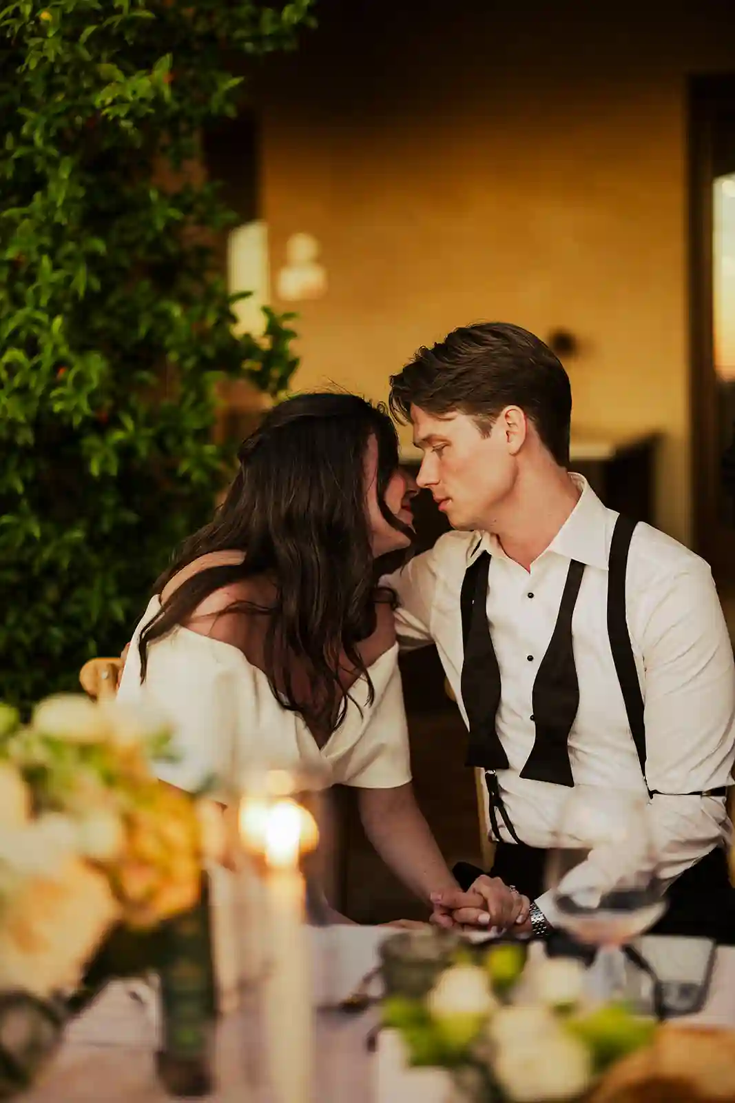 Brudeparet kysser ved middagsbordet under bryllupsfesten i Toscana Bride and groom kissing at the dinner table during their wedding celebration in Tuscany