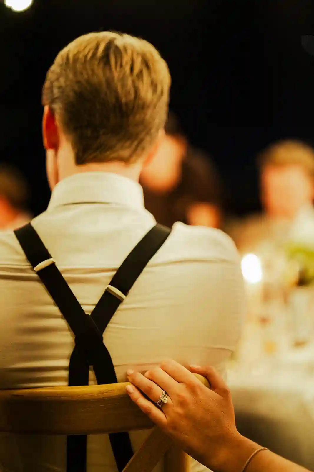 Brudens hånd med giftering på brudgommens skulder under middagen Bride’s hand with her wedding ring on the groom’s shoulder during dinner