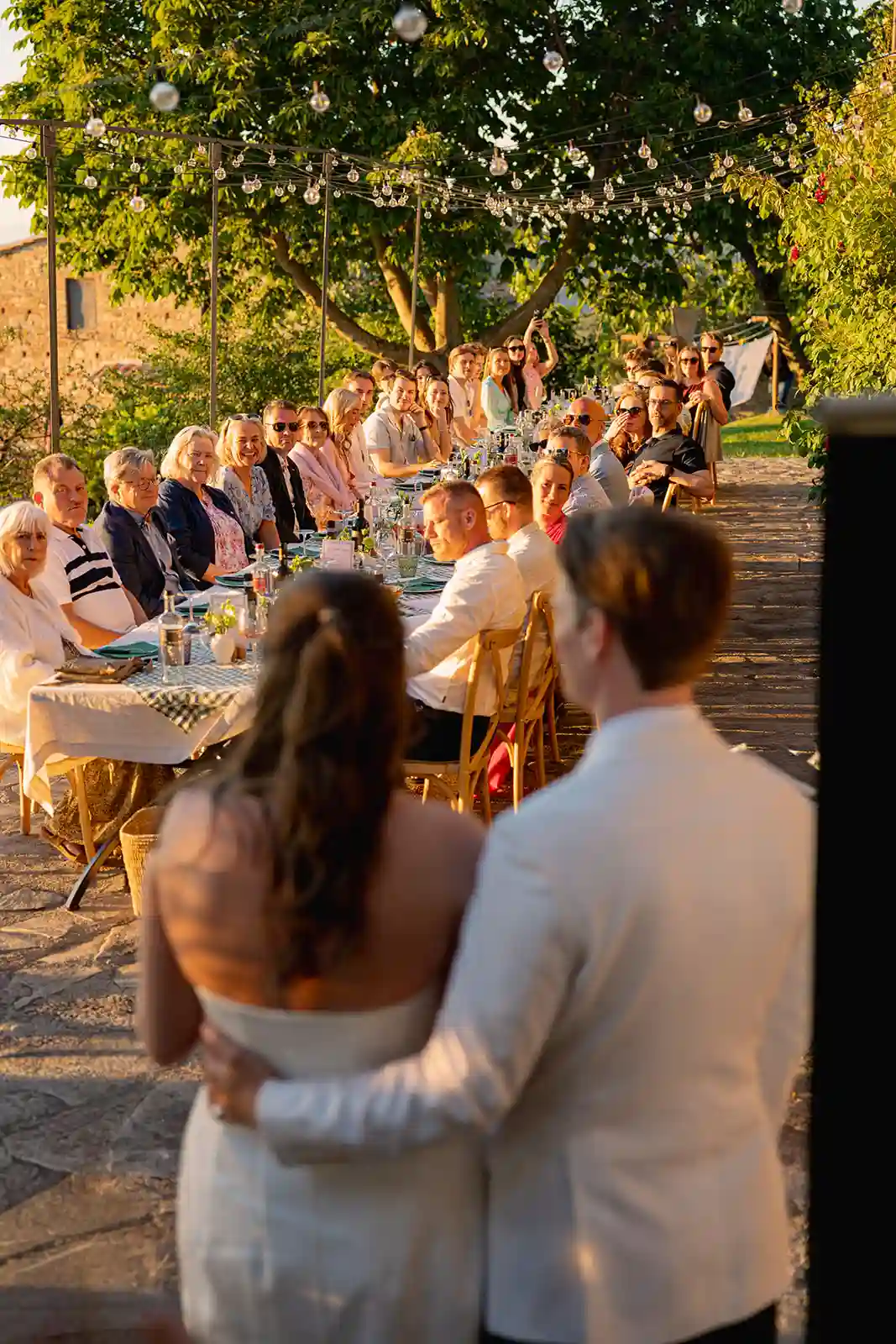 Brudepar og gjester under middag utendørs i Seggiano før bryllupet Bride and groom with their guests at an outdoor dinner in Seggiano before the wedding